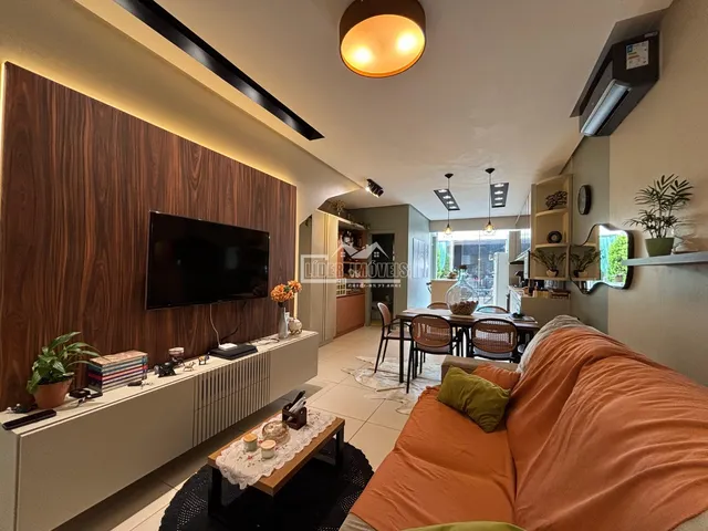 Sala de estar com sofá grande e painel de madeira na parede, com área de jantar ao fundo.