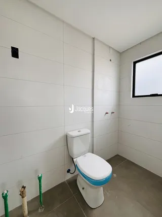Foto do interior de um banheiro com paredes brancas e piso cinza.
