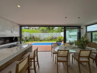 Sala de estar e jantar com vista para uma piscina no quintal.