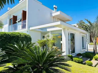 Fachada de uma residência moderna branca com jardim exuberante em Lajeado, Brasil.
