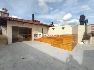 Foto da fachada de uma residência com piso de concreto e área externa de madeira.