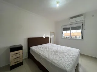 Quarto com cama de madeira e janela em ambiente claro.