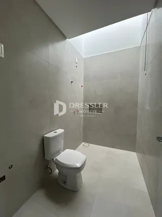 Foto de um banheiro interno com piso e paredes brancas.