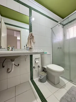 Banheiro com piso de cerâmica e detalhes em azulejos verdes.