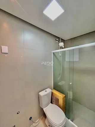 Foto de um banheiro com revestimento cerâmico e box de vidro.