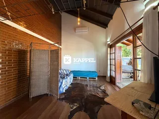 Quarto com cama azul e piso de madeira, apresentando uma parede de tijolos aparentes.