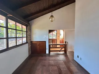 Interior de uma sala com piso de madeira e grandes janelas.