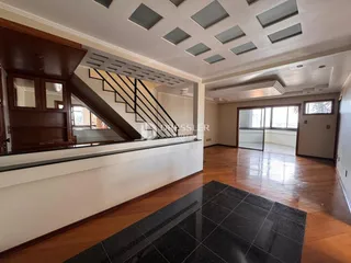 Sala de estar com piso de madeira e teto com painéis decorativos.