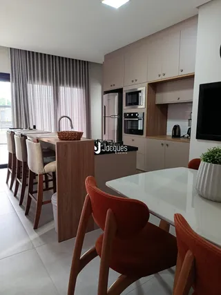 Uma sala de jantar com mesa de madeira e cadeiras em um imóvel em Lajeado.
