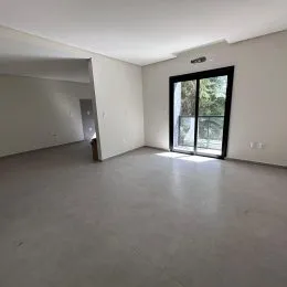 Foto de um ambiente interno amplo com piso de concreto e grande janela.