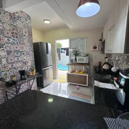 Sala de estar com piso escuro e eletrodomésticos visíveis.