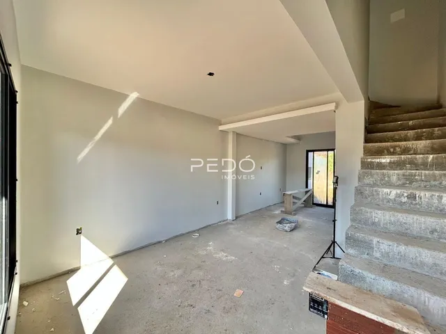Hall de entrada com paredes brancas e piso de concreto em imóvel em Lajeado.