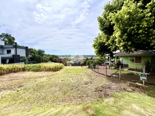 Vista externa de uma propriedade com gramado e vegetação ao redor.