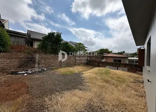 Área externa com grama seca e muro de tijolos em Lajeado.