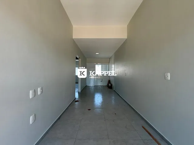 Corredor interno de um imóvel com paredes claras e piso de concreto.