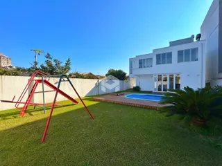 Foto da fachada de uma residência com piscina e jardim.