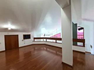 Espaço interno amplo com piso de madeira e paredes brancas.