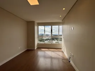 Sala de estar com piso de madeira e grande janela com vista para a paisagem.