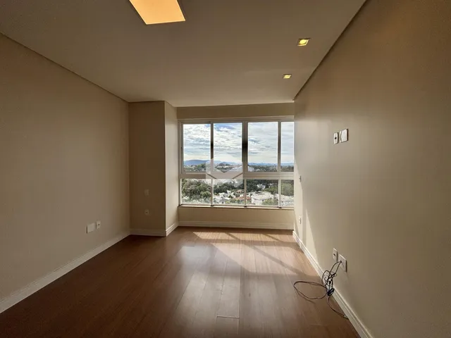Sala de estar com piso de madeira e grande janela com vista para a paisagem.
