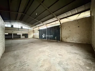 Espaço industrial interno com paredes de tijolo e teto metálico.