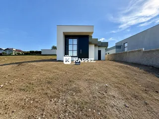 Fachada de uma casa moderna em Lajeado, Brasil, com terreno aberto em primeiro plano.