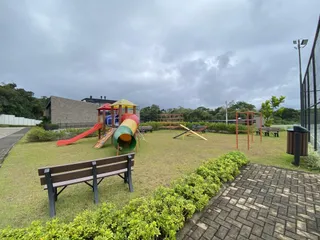 Área externa com gramado e equipamentos de playground.