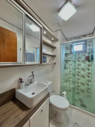 Banheiro com box de vidro e revestimento cerâmico.