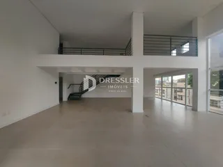 Vista interna de um espaço amplo com paredes brancas e piso claro.