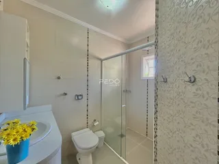 Banheiro moderno com box de vidro e revestimento de parede.