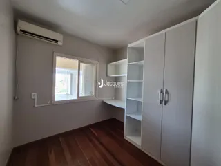Sala de estar com piso de madeira e armários brancos.