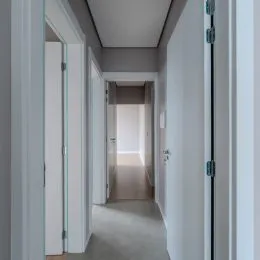 Corredor interno com paredes brancas e portas.