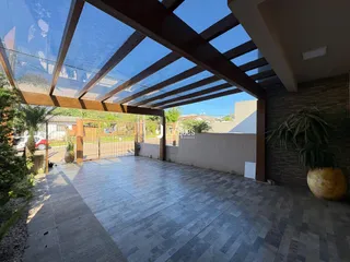 Vista externa de uma área pavimentada coberta por uma estrutura de madeira.