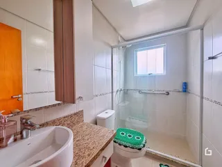 Banheiro com box de vidro e revestimento cerâmico nas paredes