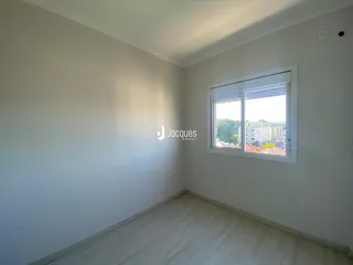 Ambiente interno de uma sala com piso de madeira clara e janela.