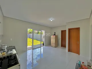 Sala de estar com piso de cerâmica e portas de vidro que dão acesso ao exterior.