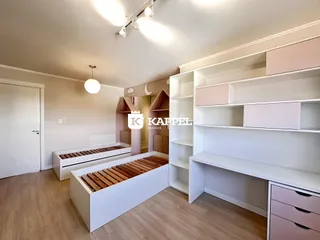 Quarto com camas de madeira e estantes brancas em um ambiente claro.