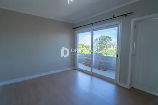 Ambiente interno com piso de madeira e porta de vidro que dá para o exterior.