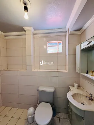 Foto de um banheiro com azulejos brancos e vaso sanitário.