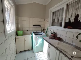 Interior de uma sala com paredes de azulejo branco e lareira.
