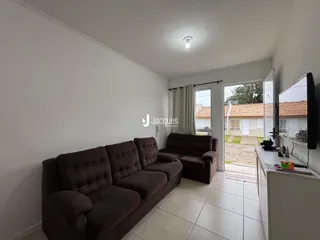 Sala de estar com sofá marrom e piso claro em imóvel no Brasil.
