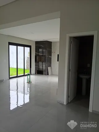Vista interna de um ambiente com piso de cerâmica e porta de vidro que dá para o exterior.