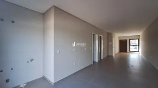 Vista de um corredor interno com paredes brancas e piso cinza claro.