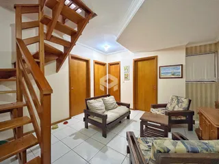Sala de estar com escadaria de madeira e portas de madeira.