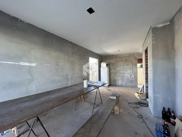 Interior de uma sala em construção com paredes de concreto expostas.
