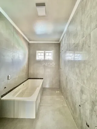 Foto de um banheiro com banheira e revestimento de cerâmica clara.