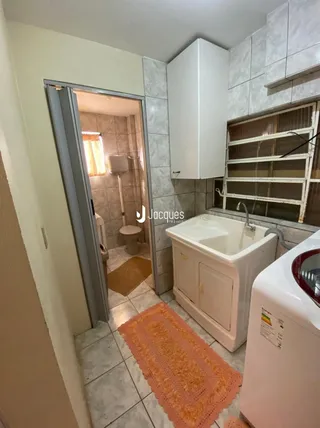Um banheiro com azulejos claros e uma bancada branca.