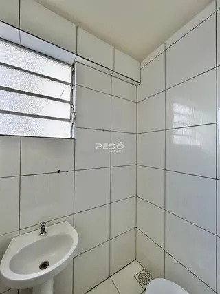 A foto mostra o interior de um banheiro com revestimento de azulejos brancos.
