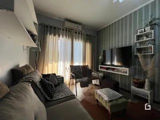 Sala de estar com sofá e janela iluminada em um apartamento no Brasil.