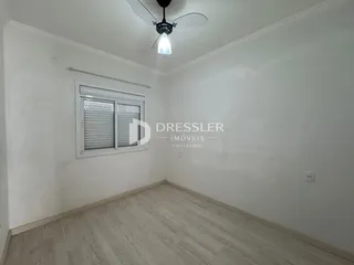 Ambiente interno de uma sala com piso de madeira clara e paredes brancas.