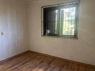 Foto de um cômodo interno com paredes brancas e piso de madeira.